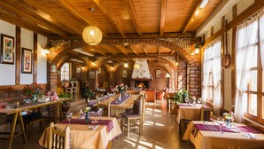 A restaurant with wooden beams and brick walls, featuring tables and chairs set for dining. - Copacabaña Lodge (Carhuaz)