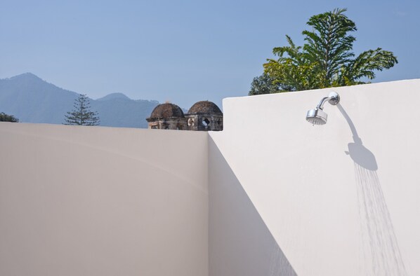 A modern shower with a clear view of a mountain range and a building with domed structures in the background.