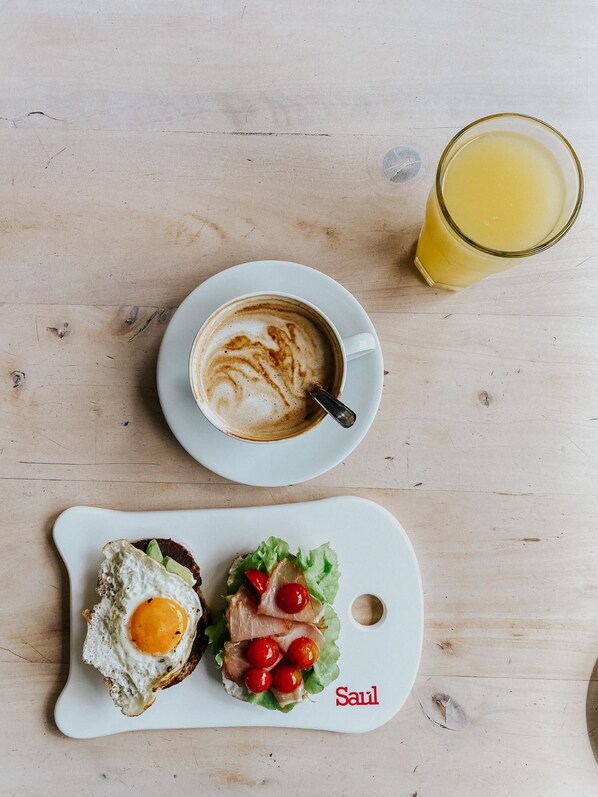 Desayuno con una taza de café, un vaso de jugo de naranja y un plato con huevo y ensalada.