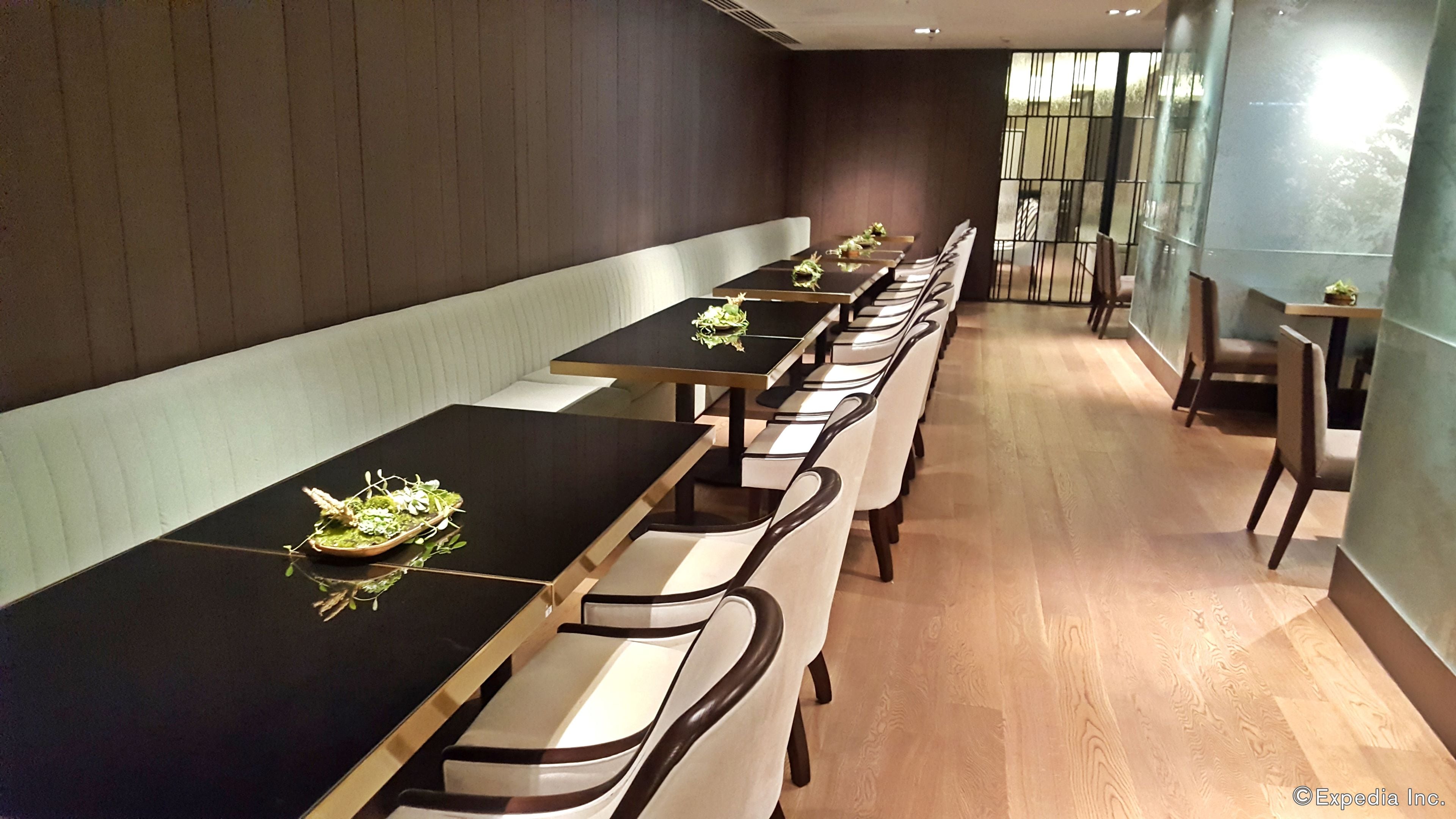A long dining table with chairs, a bench, and a small table with a plant.