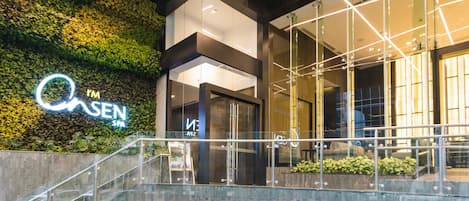 Un edificio moderno con fachada de vidrio, entrada visible y una escalera que lleva a un nivel superior.