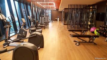 Une salle de sport équipée de matériel d’exercice, dotée d’un plancher en bois et de grandes fenêtres.