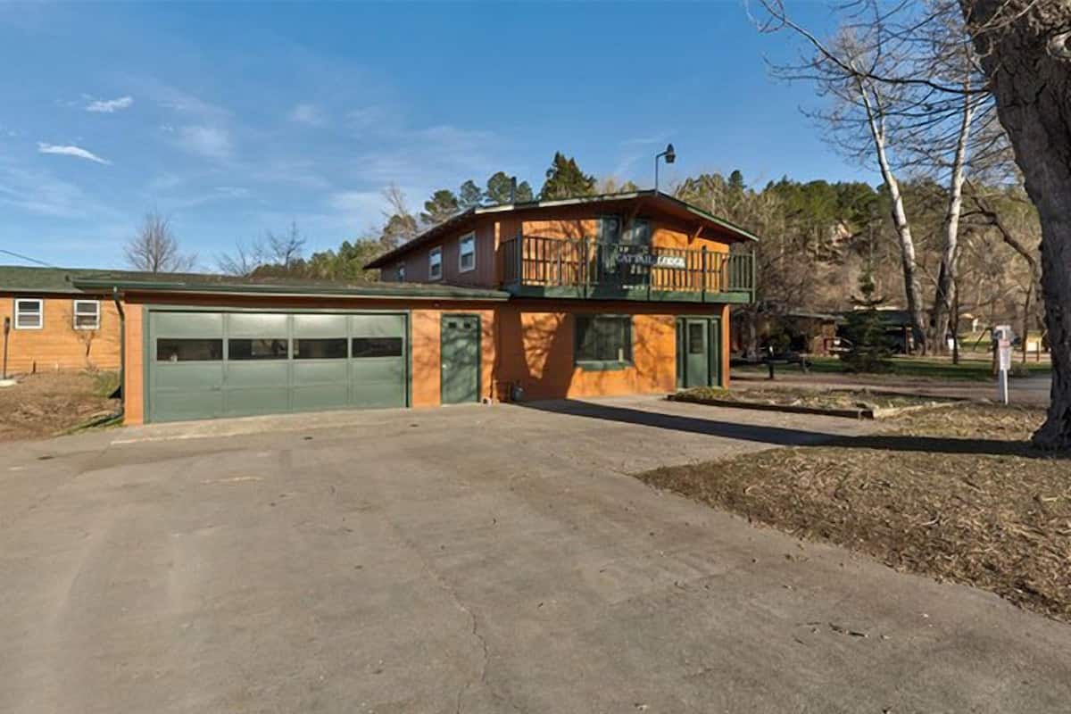 Un bâtiment à deux étages avec une porte de garage verte, un balcon à l’étage supérieur et un ciel dégagé.