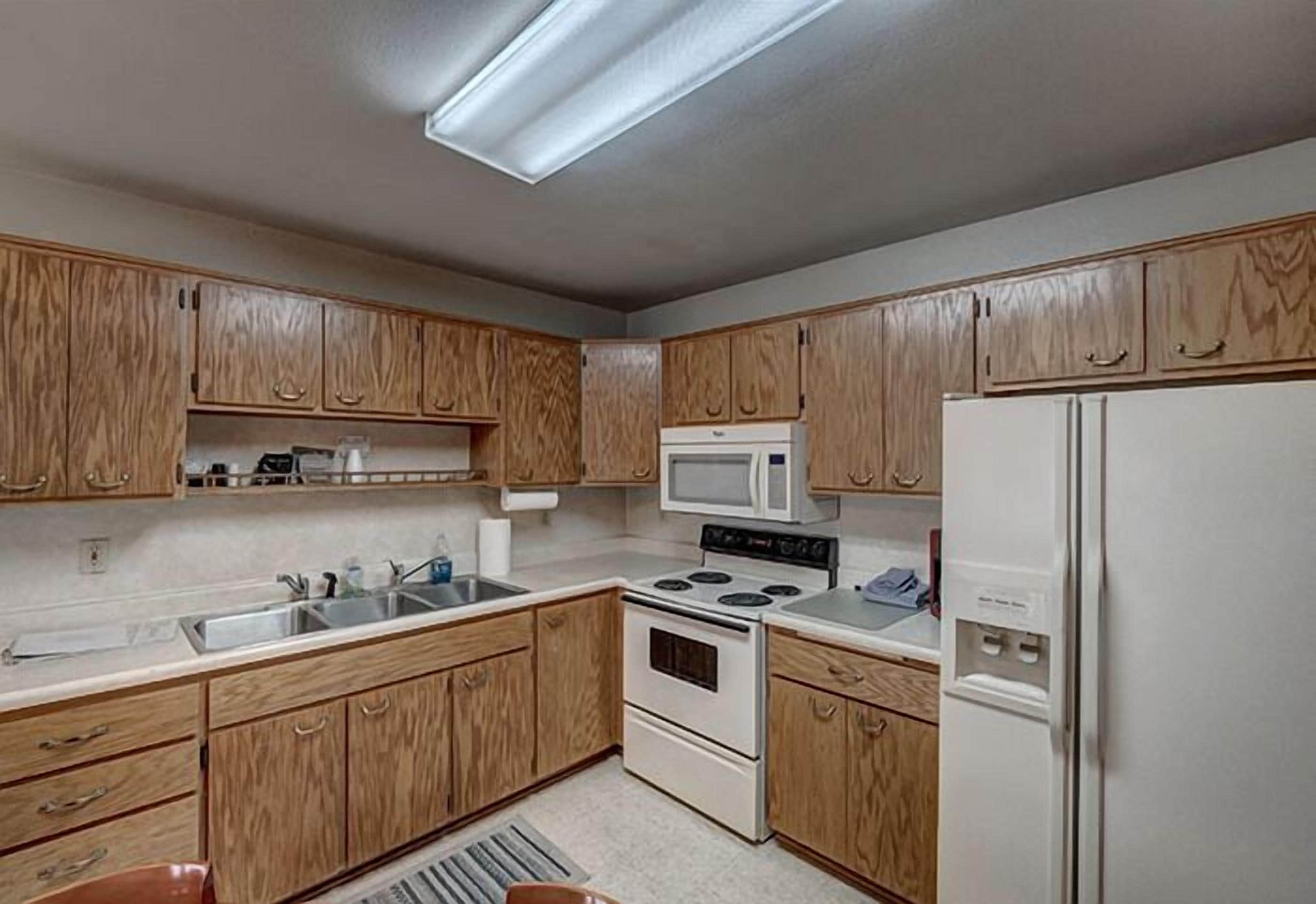 A kitchen with wooden cabinets, a microwave, a stove, and a refrigerator.