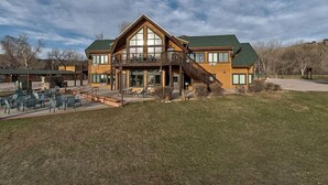 Ein großes Holzhaus mit Balkon, Sitzgelegenheiten im Freien und einer Rasenfläche davor.