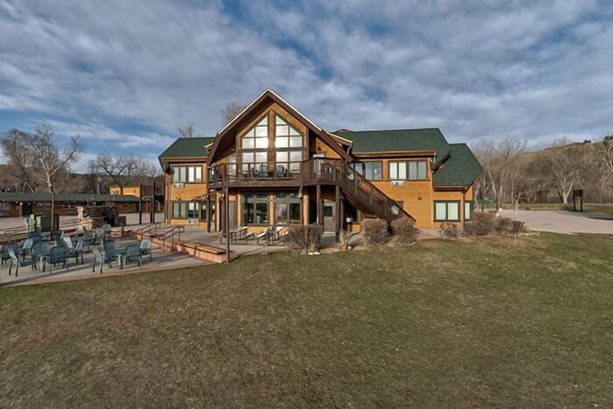 Un grand bâtiment en bois doté d’un balcon, d’un espace extérieur aménagé pour s’asseoir et d’une pelouse devant.