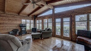 Ein großzügiges Holzblockhaus-Interieur mit Holzbalkendecke, großen Fenstern und einer gemütlichen Sitzecke.