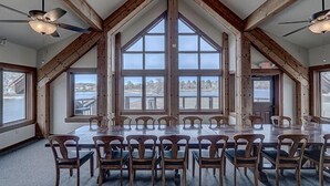 Ein großzügiger Speisesaal mit hoher Decke und großen Fenstern mit Blick auf ein Gewässer.