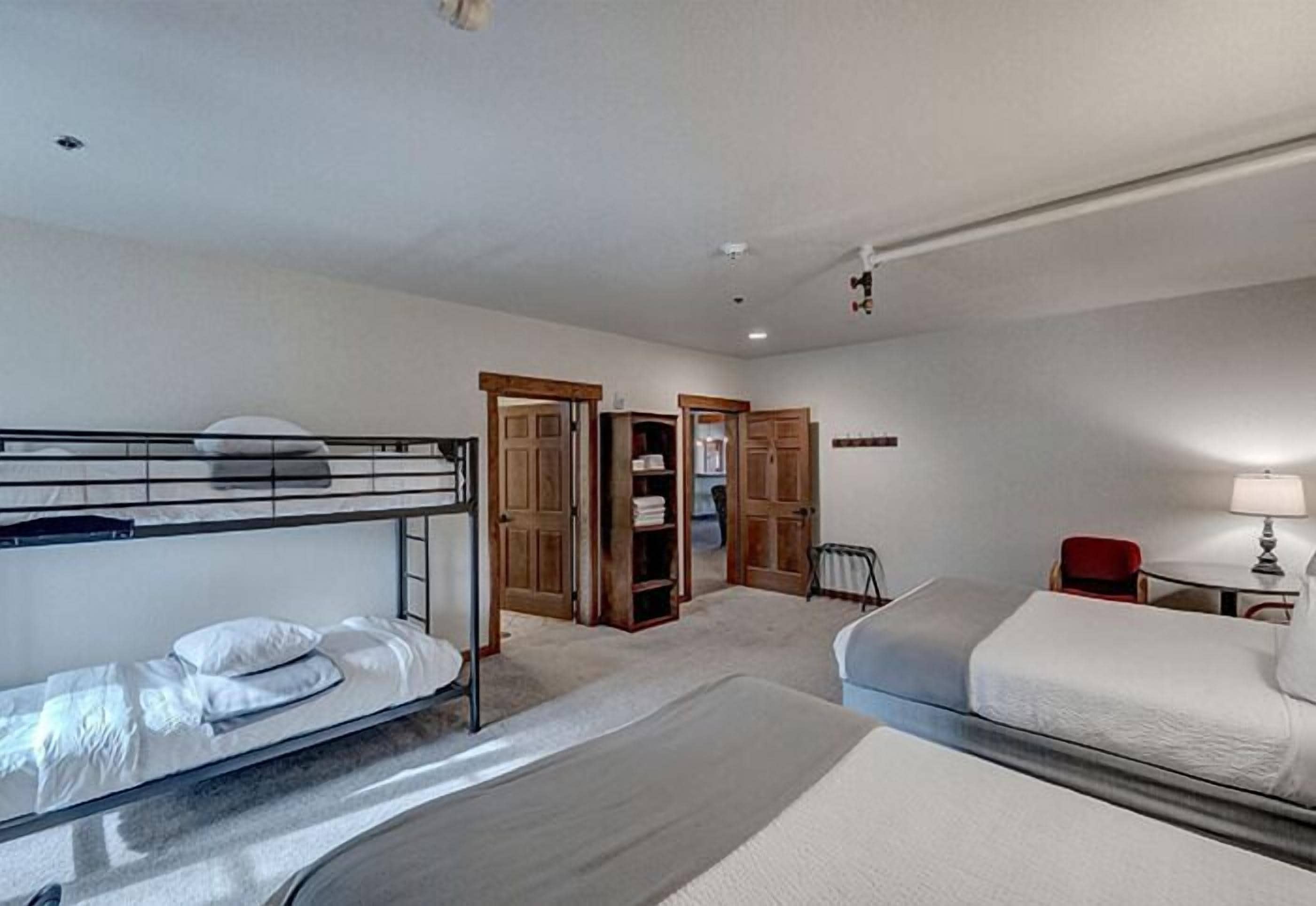 Una habitación de hotel con literas, un escritorio, una silla y un armario.