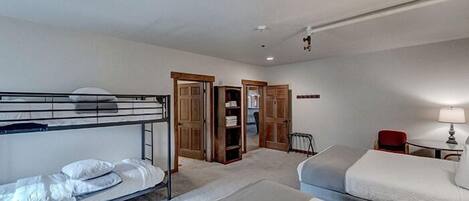 Una habitación de hotel con literas, un escritorio, una silla y un armario.