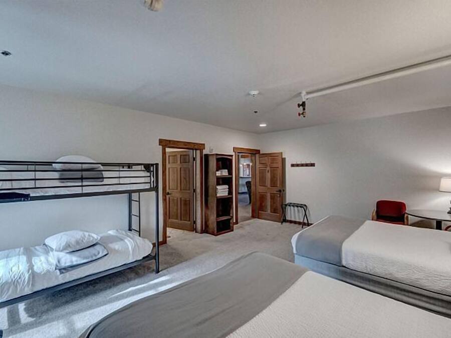 A hotel room with bunk beds, a desk, a chair, and a wardrobe.