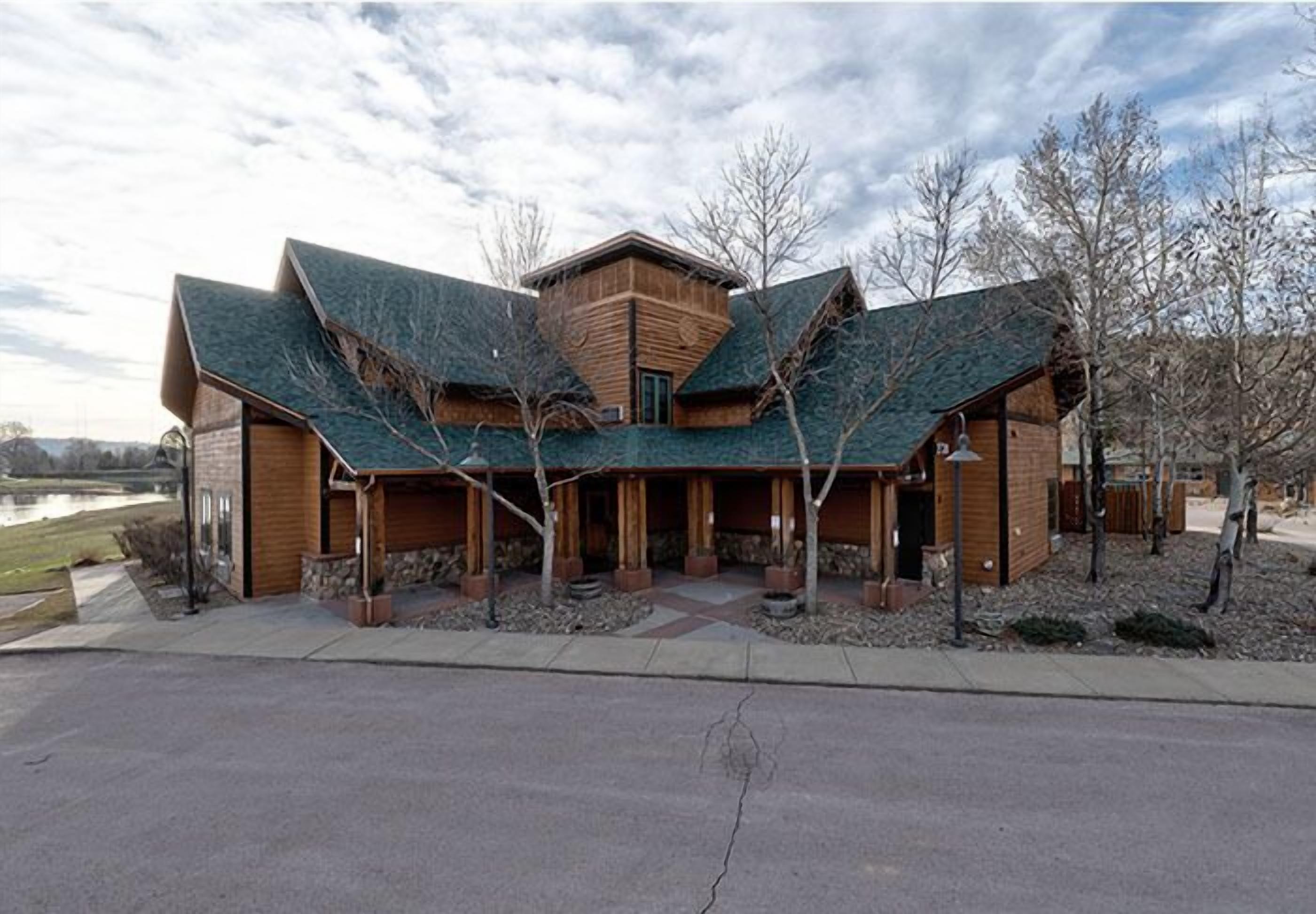 A modern building with a unique roof design, wooden exterior, and a landscaped front yard.