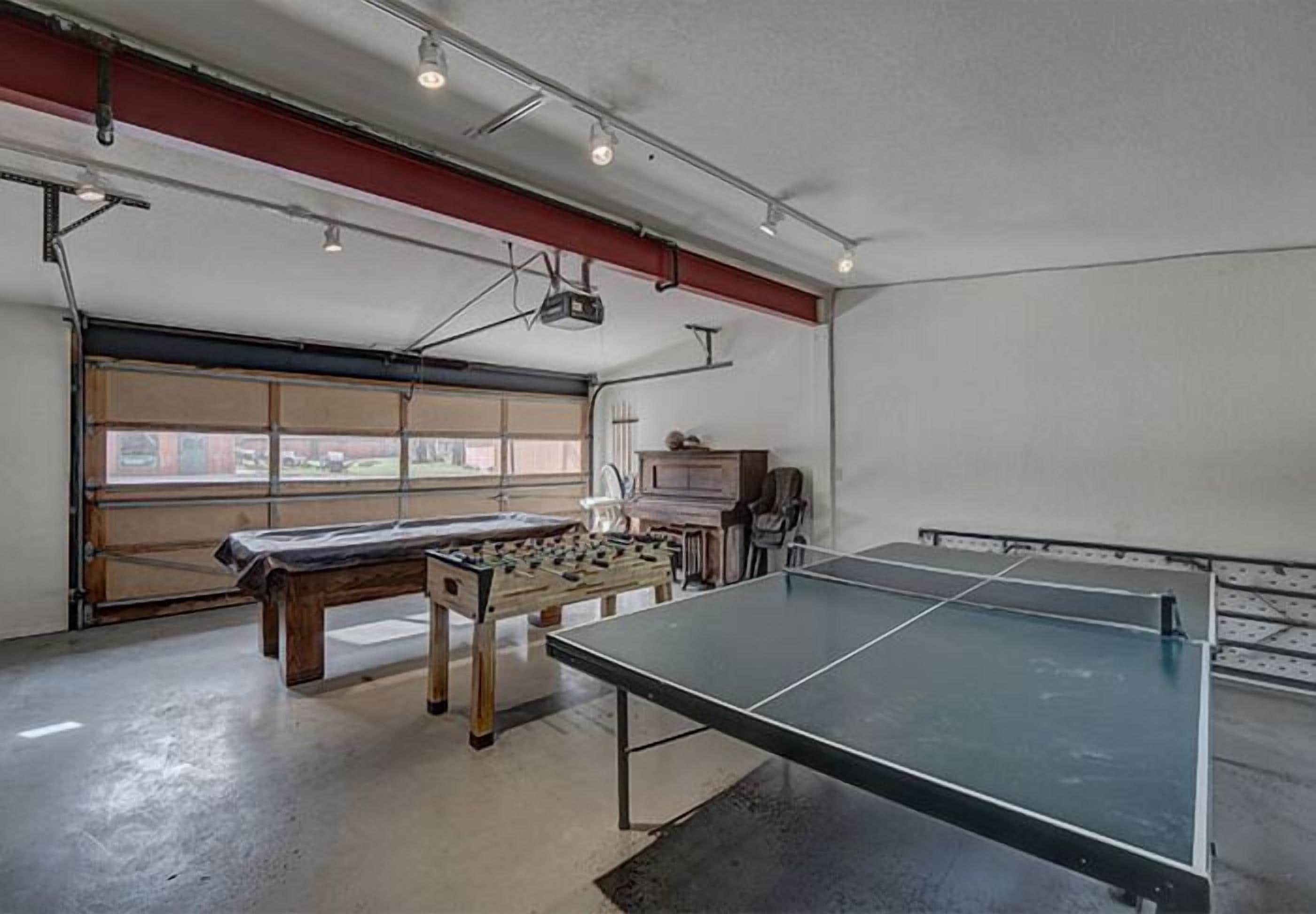 Une pièce spacieuse équipée d’une table de ping-pong, d’un baby-foot et d’une grande fenêtre.