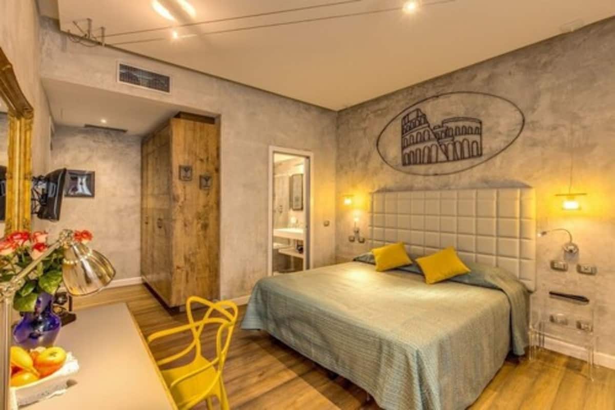 A bedroom with a bed, a wooden wardrobe, a mirror, and a wall with a circular design.