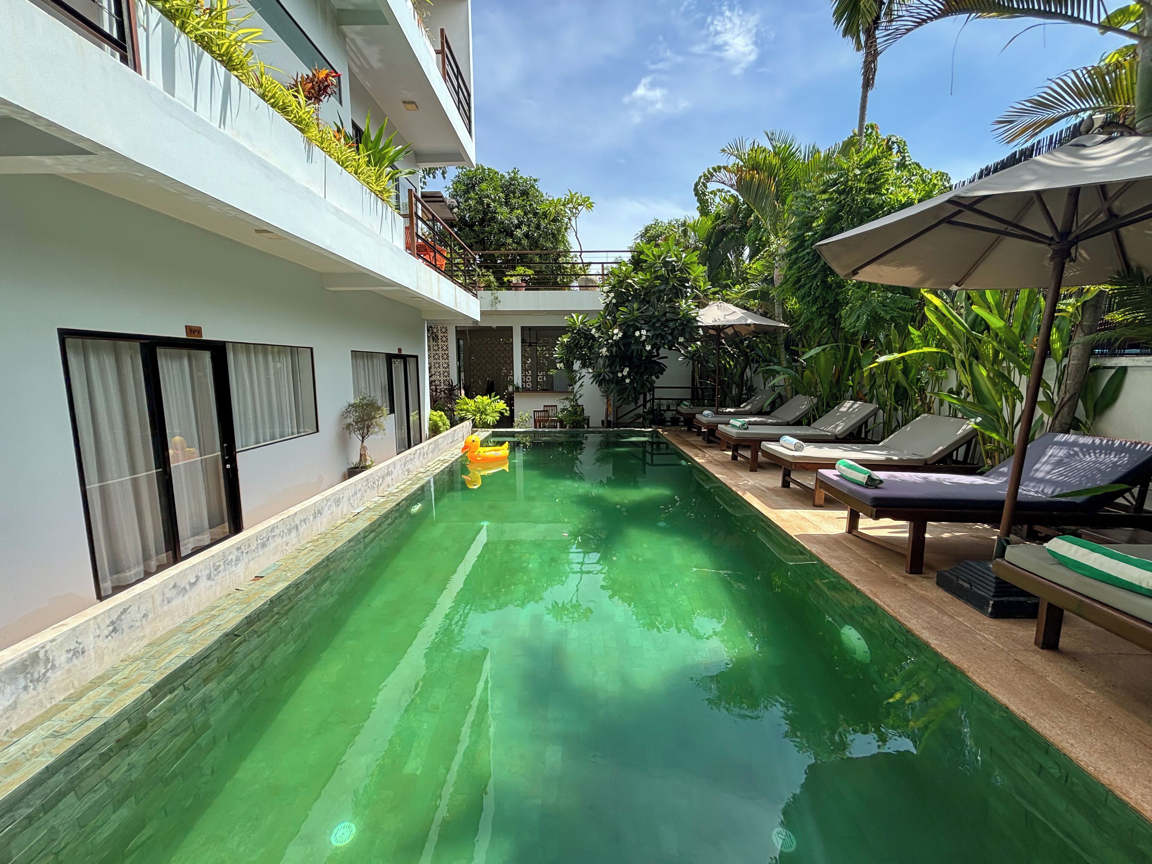 Una piscina al aire libre, sillones reclinables de piscina