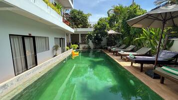 Una piscina al aire libre, sillones reclinables de piscina