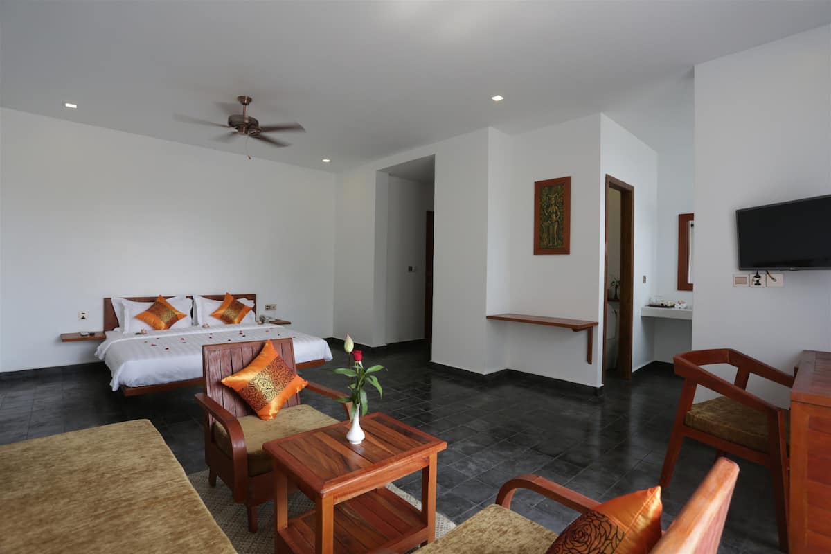 A hotel room with a bed, a desk, a chair, a television, and a ceiling fan.