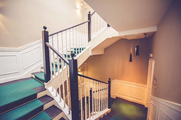 A staircase with white railings and green carpeted steps.