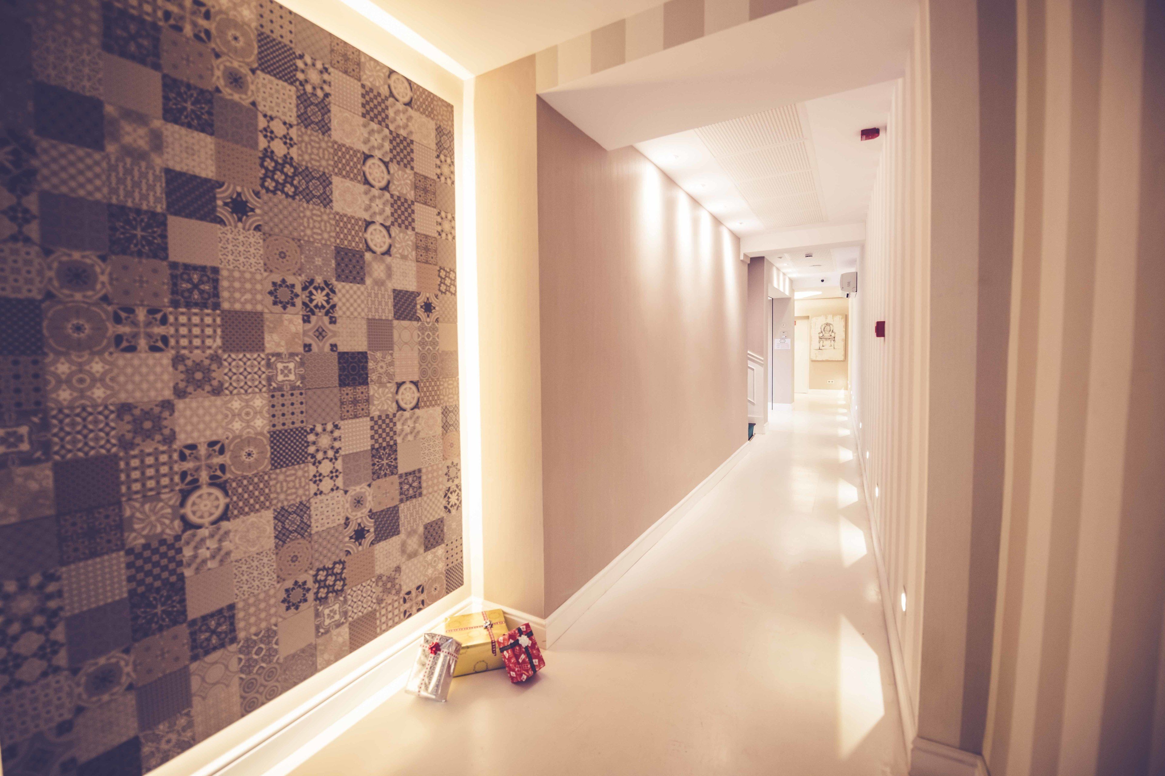 A hallway with patterned wallpaper, a white floor, and two wrapped gifts.