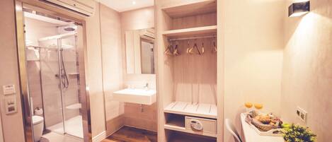 A modern bathroom with a walk-in shower, a vanity with a sink, and a built-in storage unit with shelves and hooks.