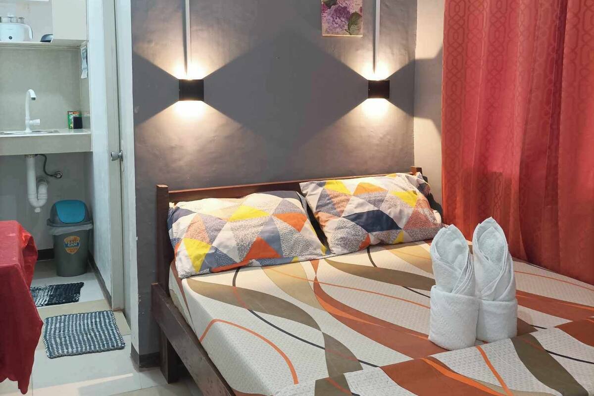 A bedroom with a bed, a red curtain, and two wall-mounted lights.