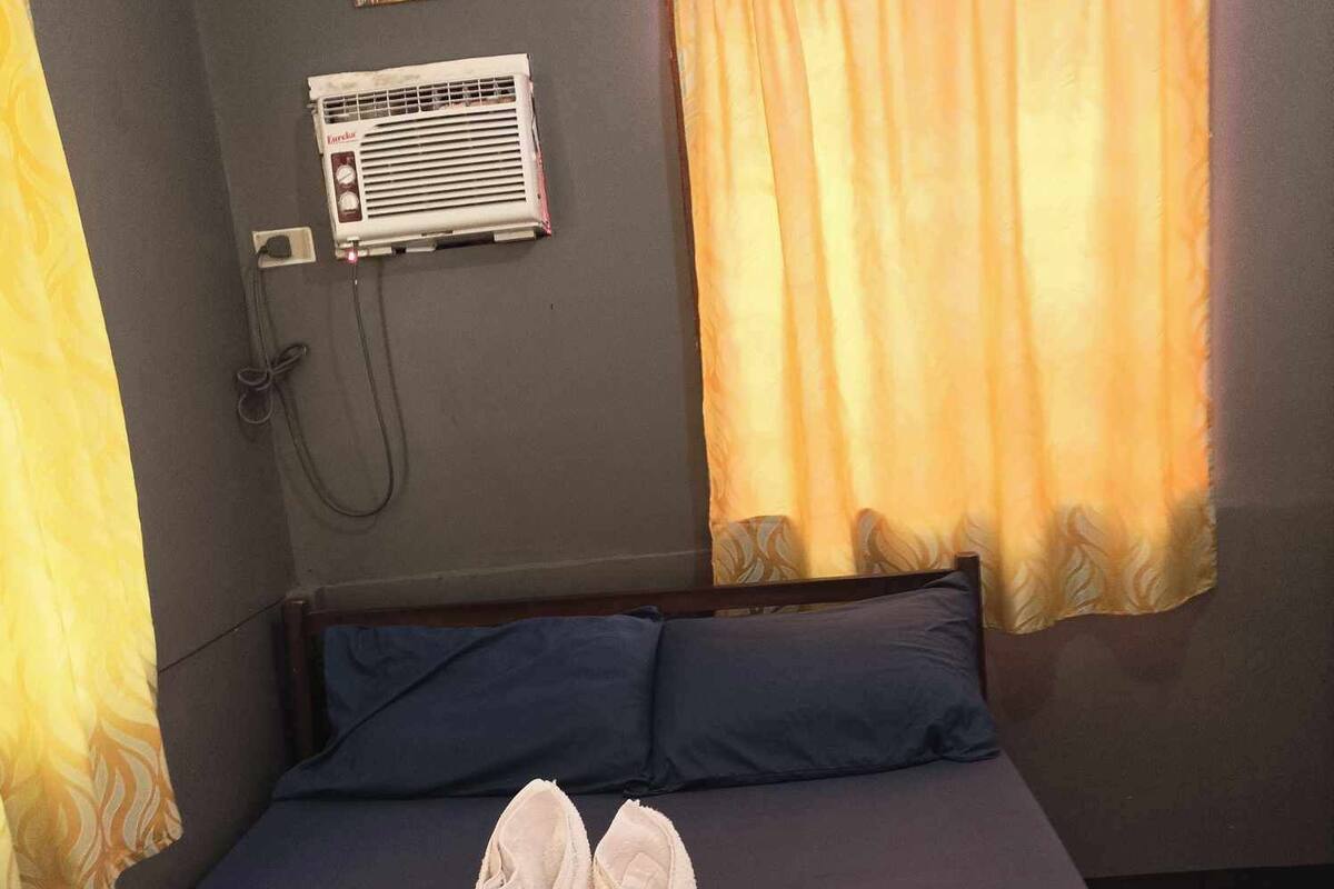A bed with a blue mattress, two pillows, and a pair of towels placed on the bed.