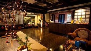 Un interior japonés tradicional con suelo de tatami, un mostrador de recepción y una zona de estar con cojines.