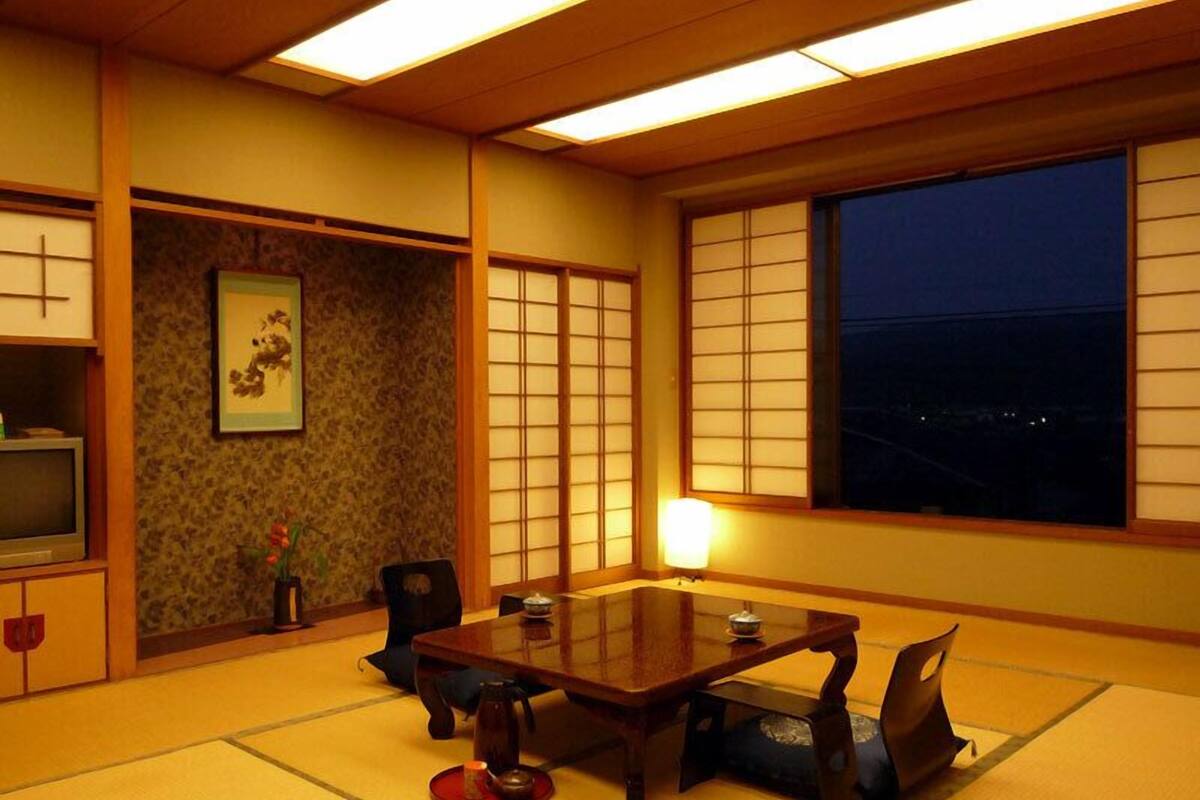 Una habitación japonesa tradicional con suelo de tatami, una mesa baja y paneles shoji.