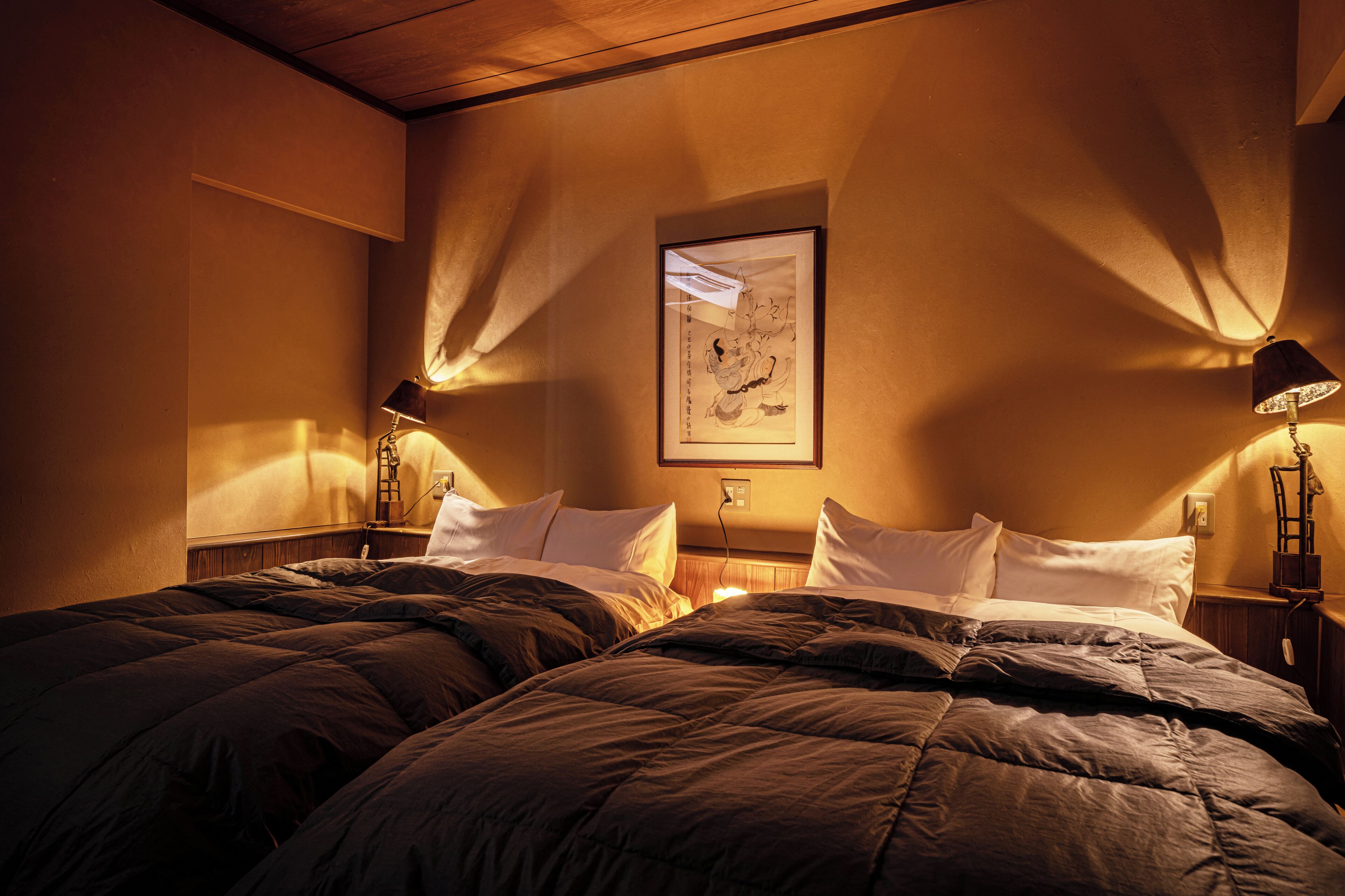Habitació d'hotel amb dos llits, una obra d'art emmarcada a la paret i dues làmpades de nit.