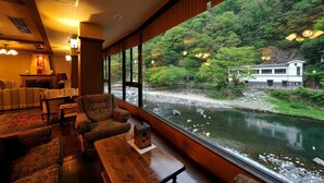 Quarto com vista para um rio e uma floresta, mobiliário de madeira e estética japonesa tradicional.