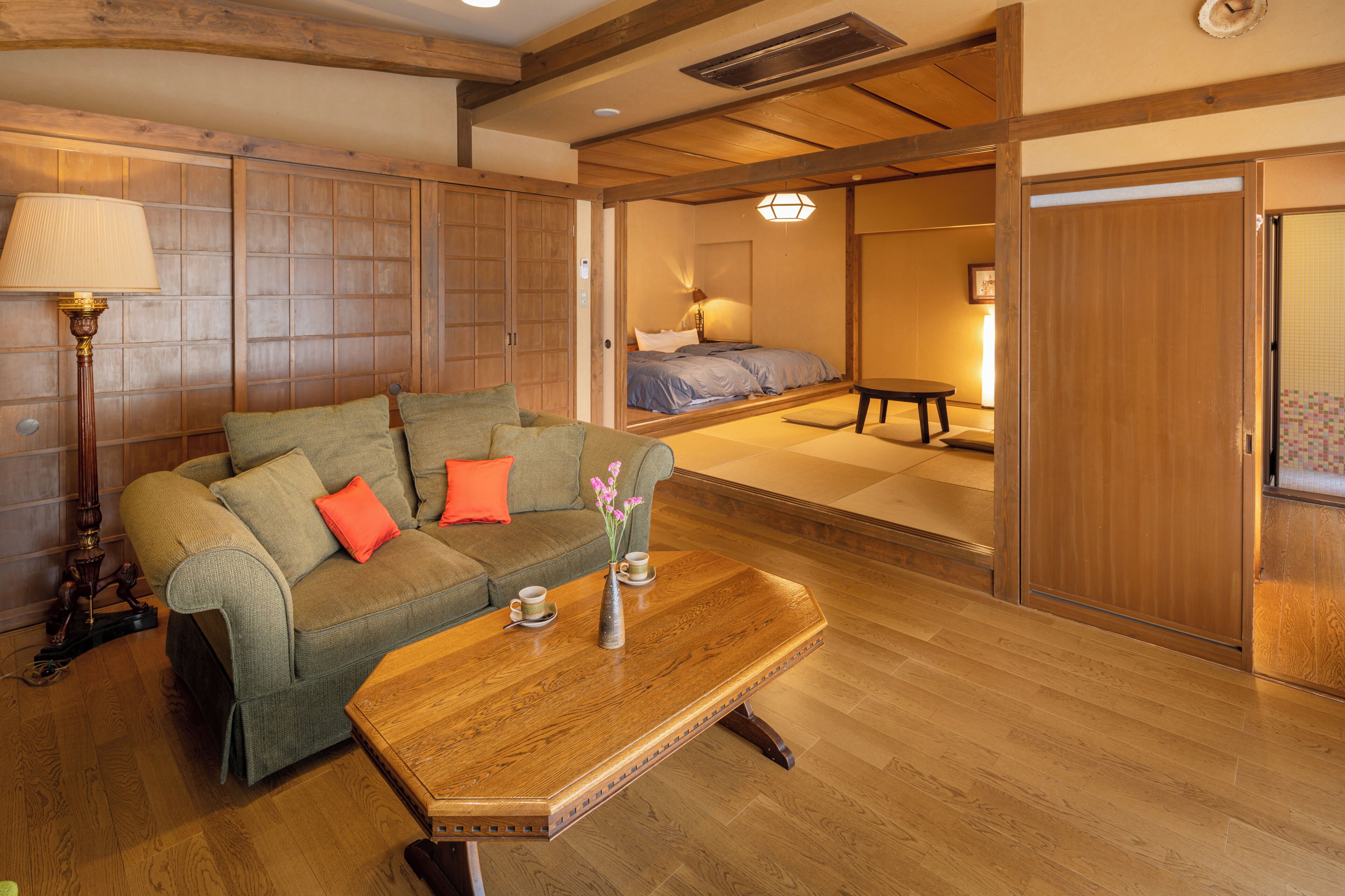 A traditional Japanese-style room with tatami flooring, a low wooden table, and a sofa with cushions.