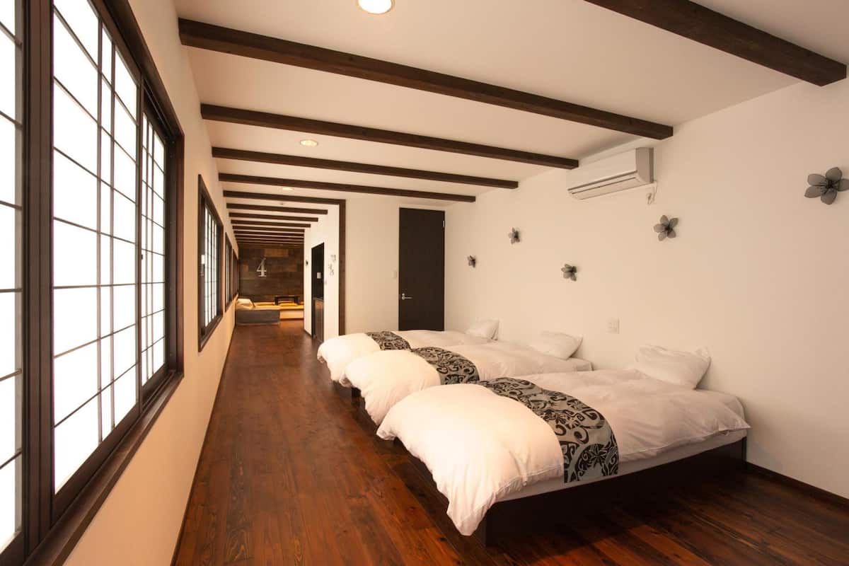 Une chambre d’hôtel avec un grand lit, un plancher en bois et un long couloir avec des fenêtres.