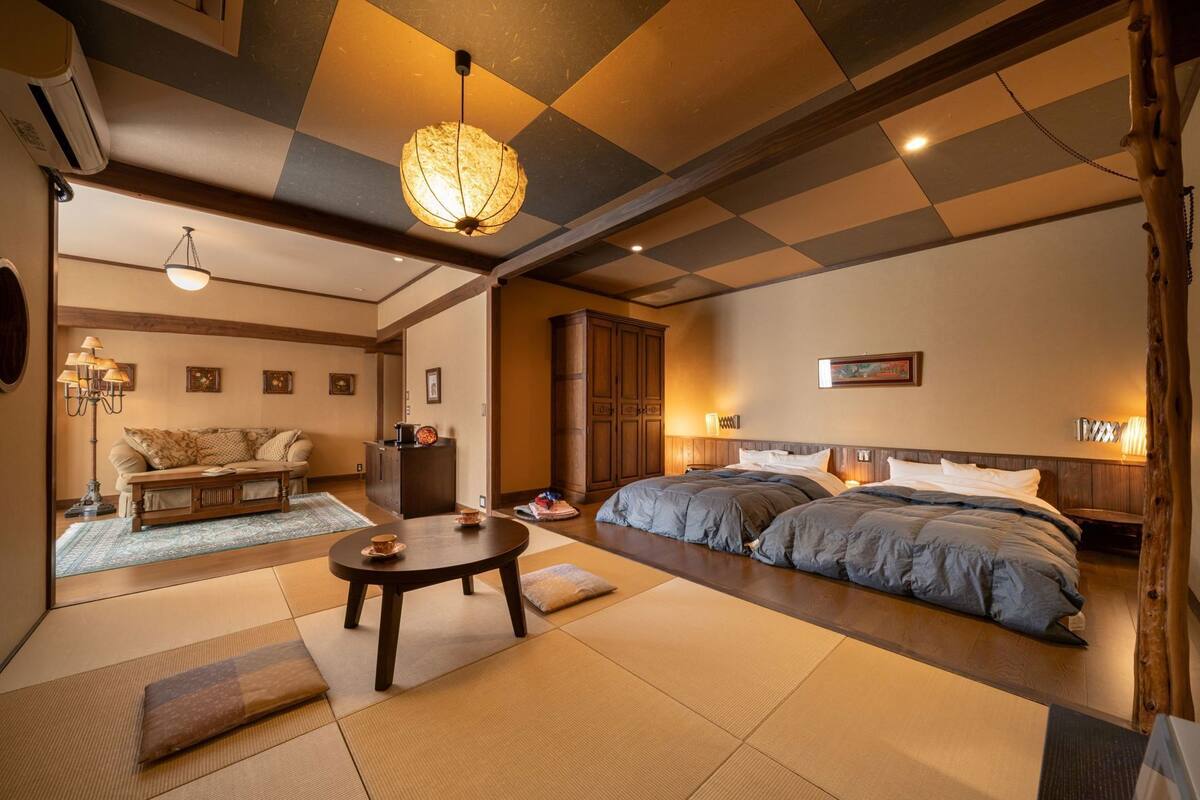 Une pièce de style japonais traditionnel, avec un sol recouvert de tatamis, un lit bas en bois, une table en tatami et une lanterne en papier suspendue.
