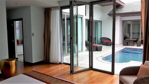 A room with a sliding glass door leading to an outdoor area with a pool and furniture. - Private Pool Villas Phuket - Mandala Arnalia (Choeng Thale)
