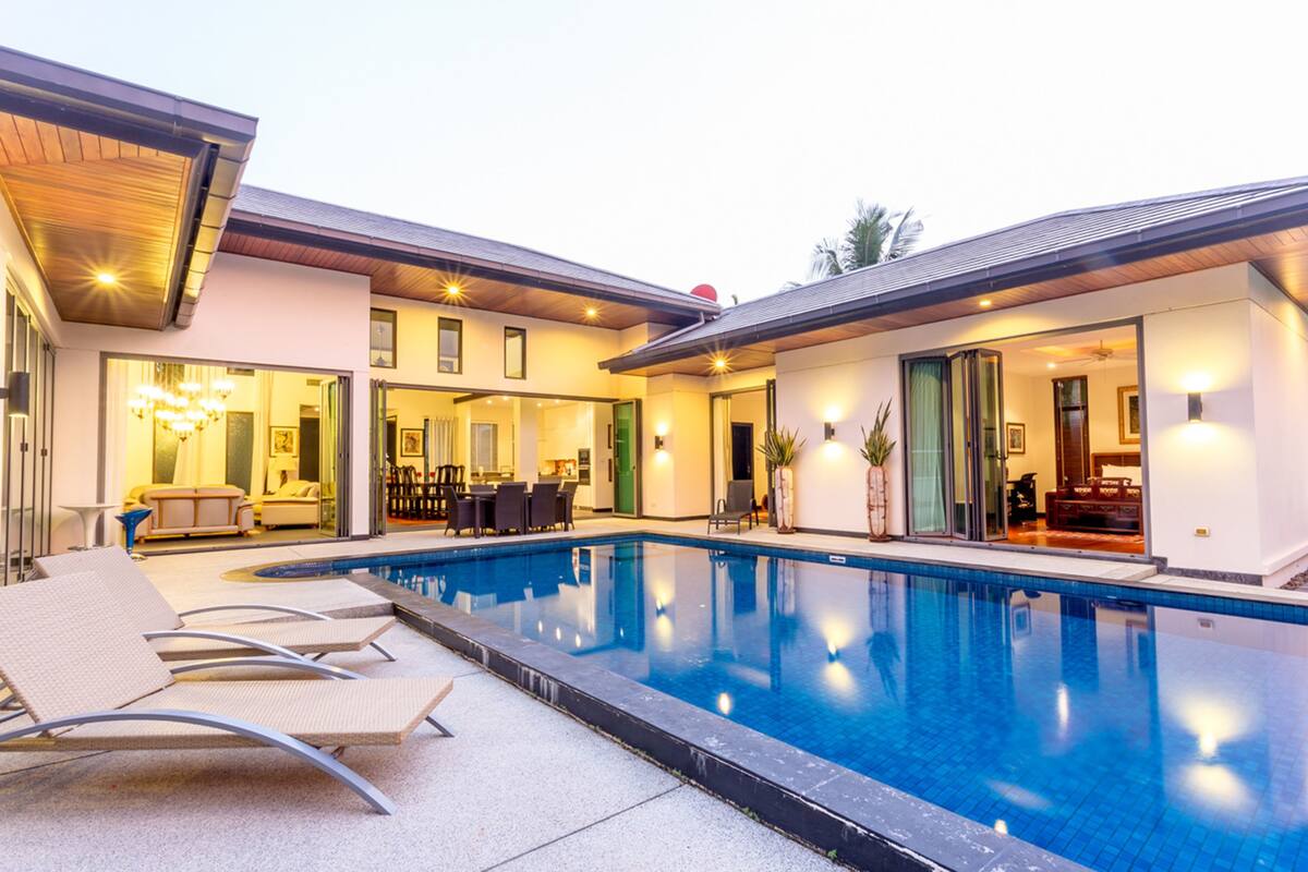 A modern pool area with lounge chairs, a dining area, and a well-lit interior.