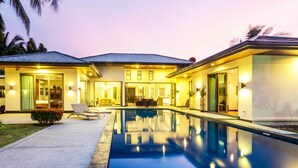 A modern house with a swimming pool, a covered patio, and a well-lit entrance. - Private Pool Villas Phuket - Mandala Arnalia (Choeng Thale)