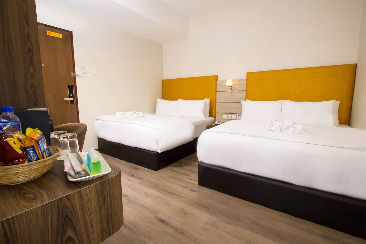 A hotel room with two beds, a wooden desk with toiletries, and a door with a sign.