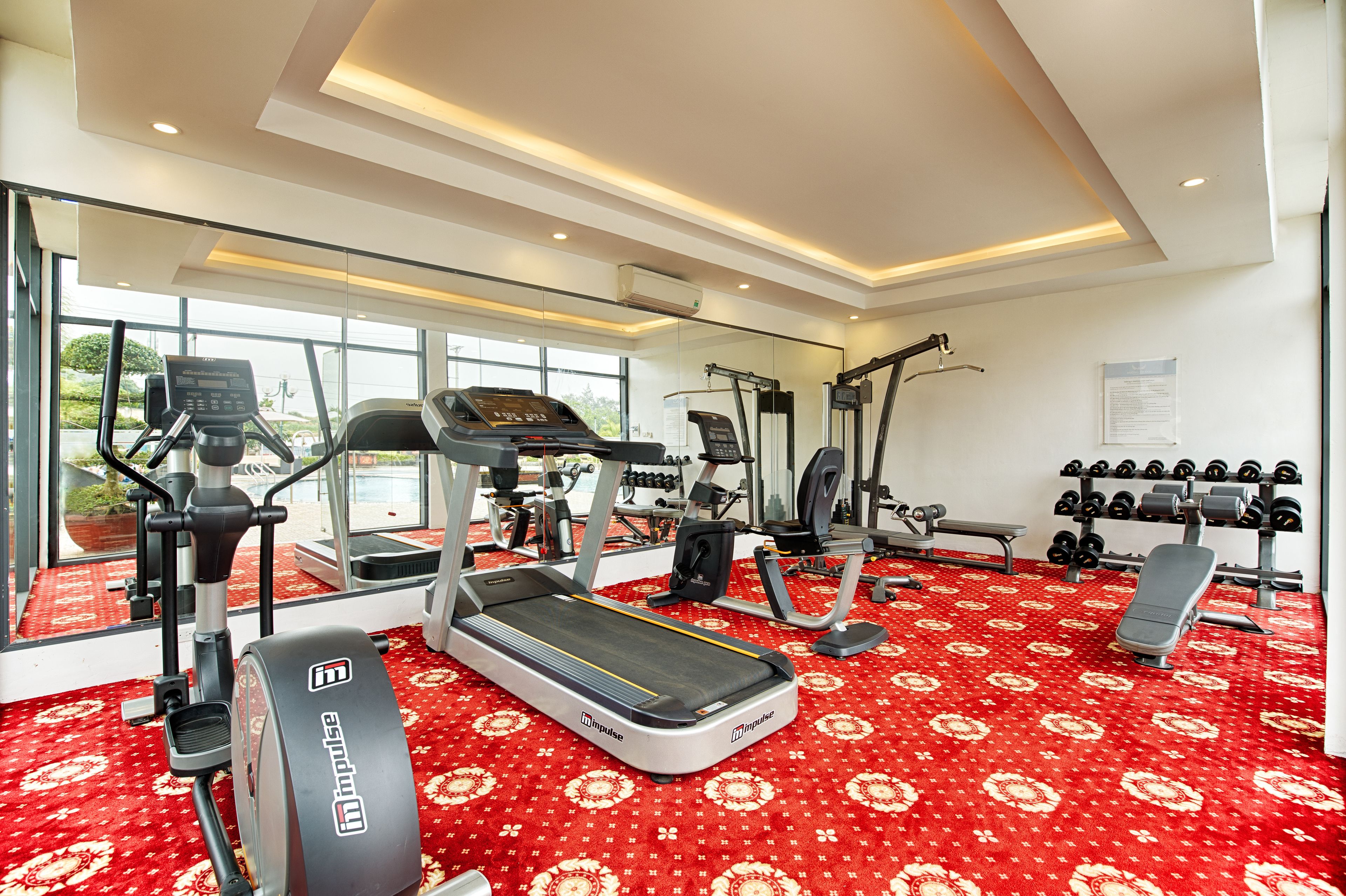 Un gimnasio con cintas de correr, elípticas y bancos de pesas.