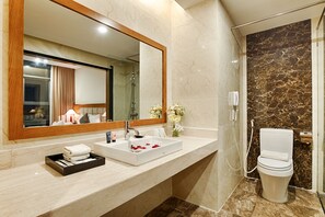 Een moderne badkamer met een grote spiegel, een wastafel, toilet en douche.