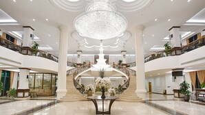 Eine beeindruckende Lobby mit einem zentralen Kronleuchter, einer Treppe und einer Rezeption.
