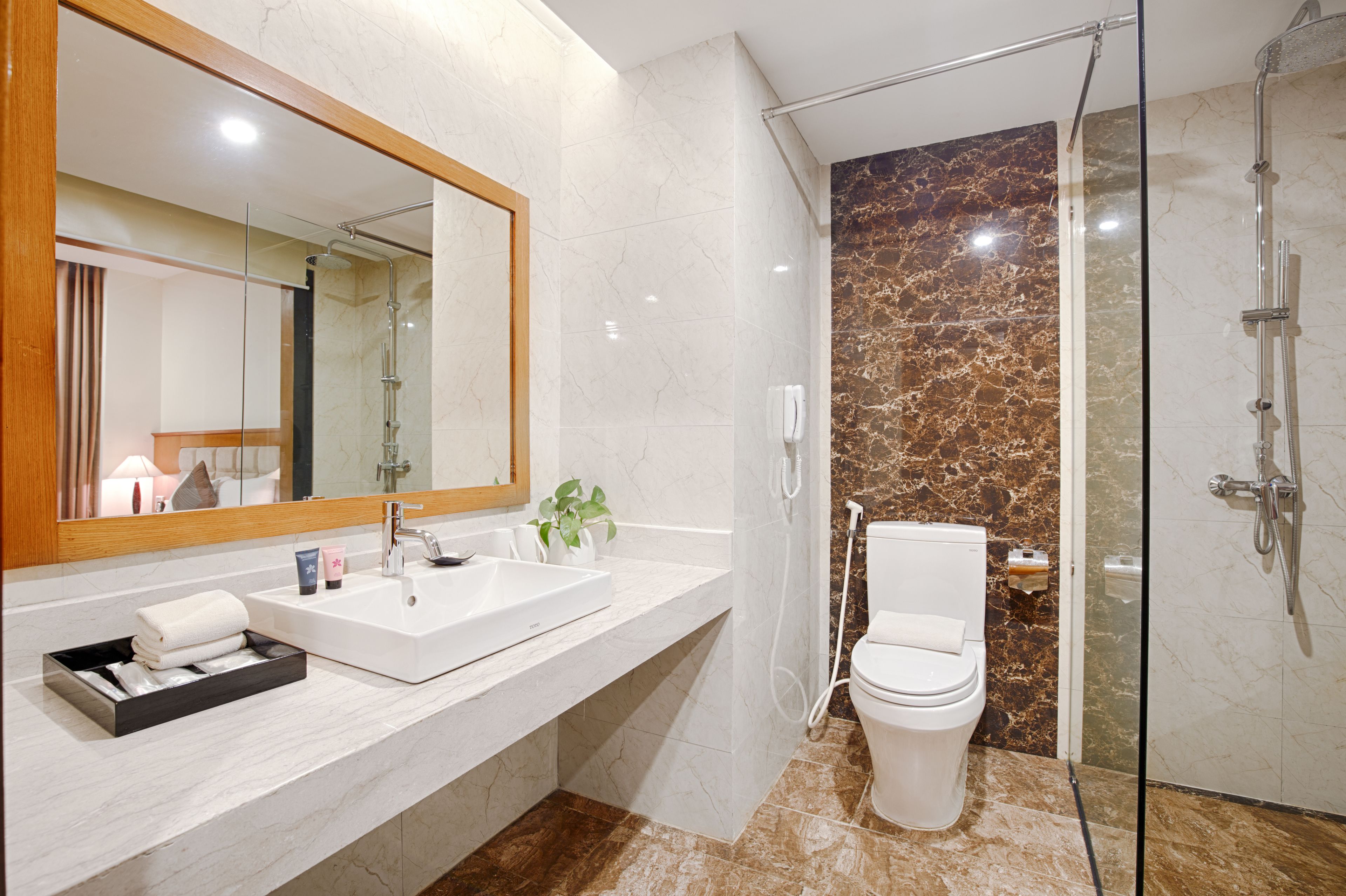 A modern bathroom with a large mirror, white sink, and a glass-enclosed shower area.