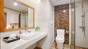 A modern bathroom with a large mirror, white sink, and a glass-enclosed shower area.