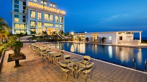 Ein Hotel mit Pool, Sitzgelegenheiten im Freien und Meerblick.