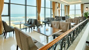 Ein Restaurant mit einer langen Theke, großen Fenstern und Blick auf den Strand.
