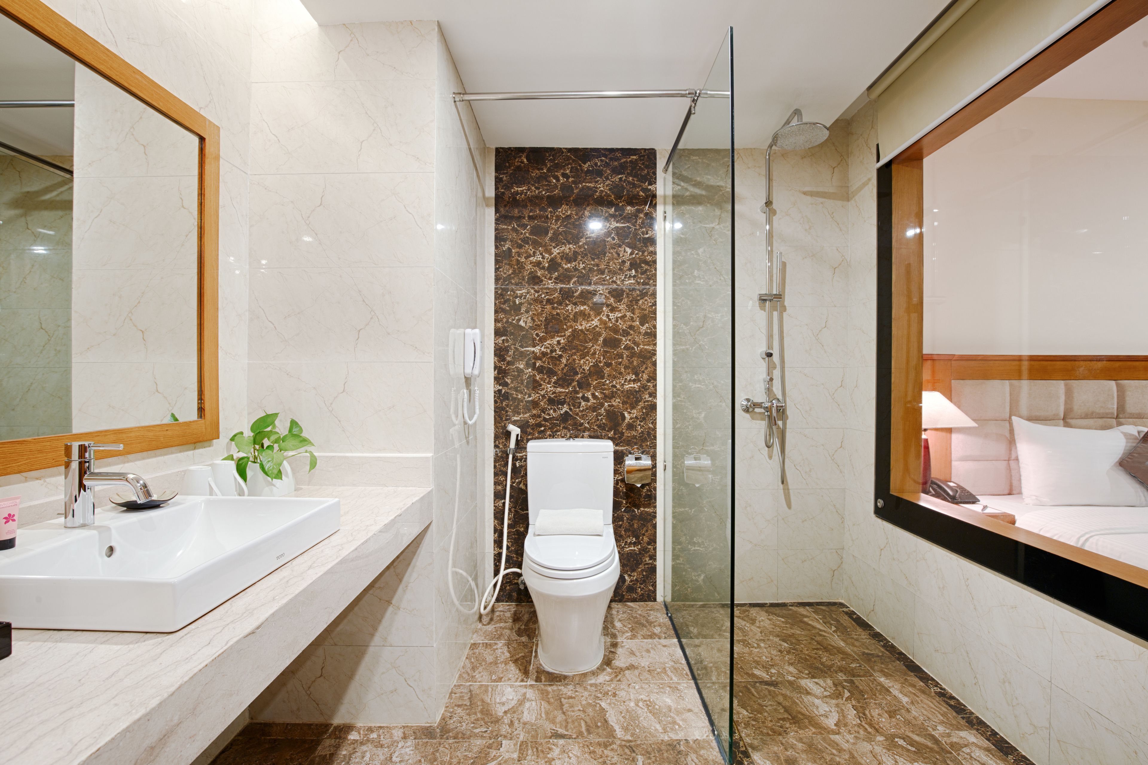 A modern bathroom with a glass-enclosed shower, a white sink, and a marble-tiled floor.