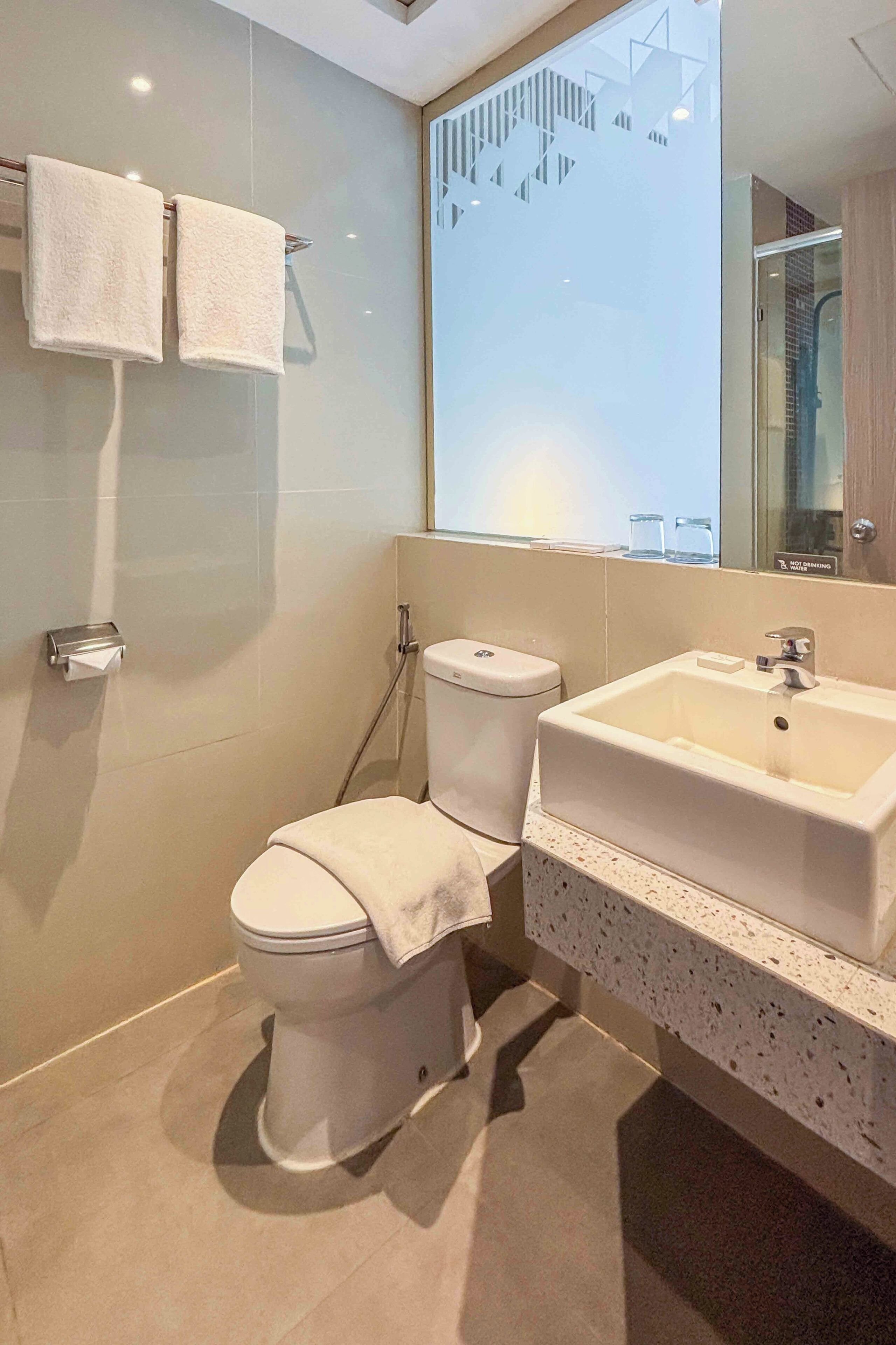 A modern bathroom with a toilet, sink, and glass shower enclosure.