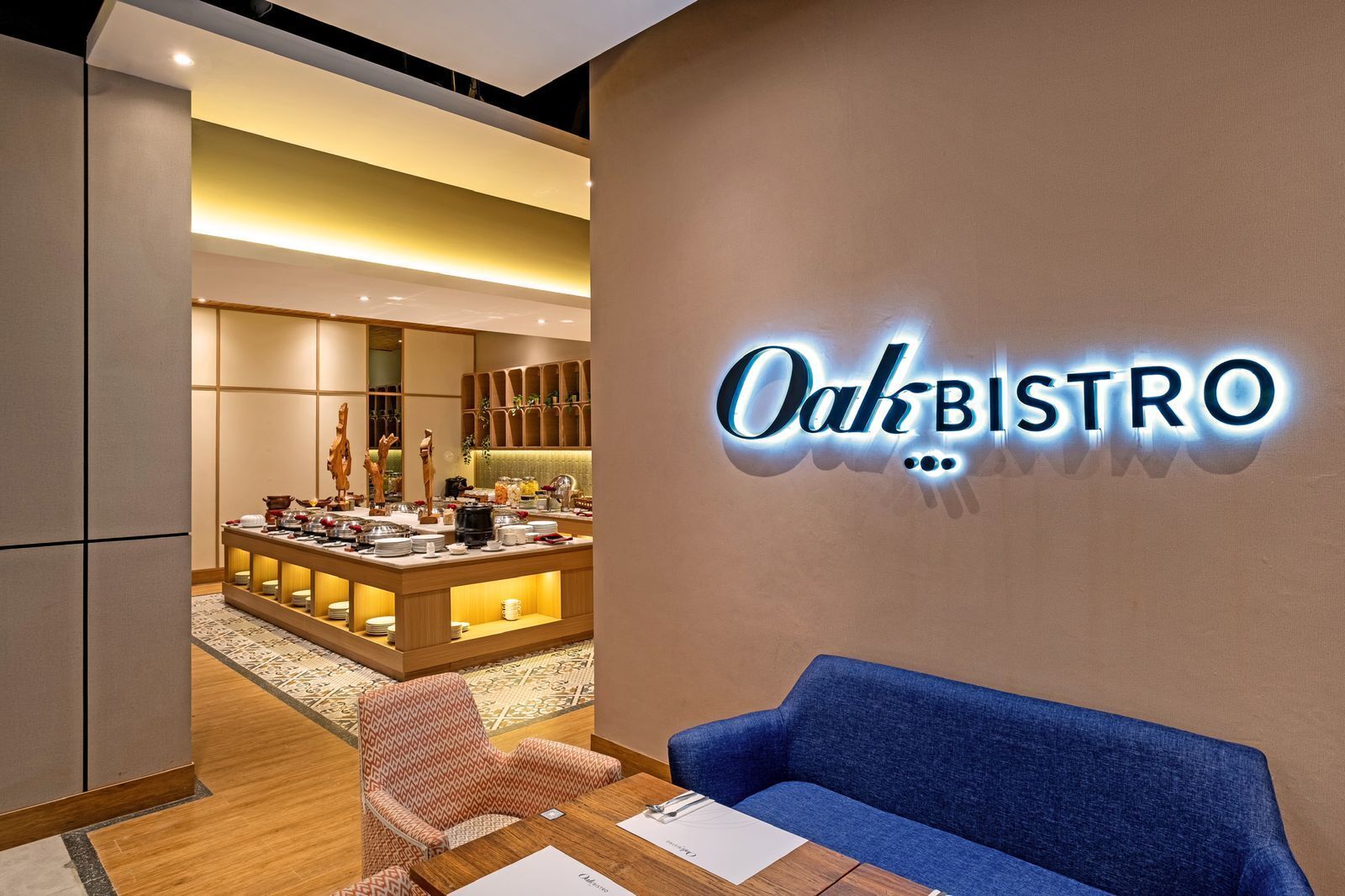 A modern bistro with a wooden counter, seating area, and a neon sign reading "Oak Bistro".