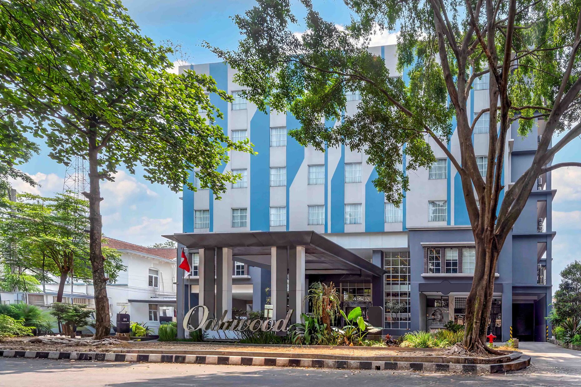 A multi-story hotel with a modern facade, a covered entrance, and a landscaped area with trees.