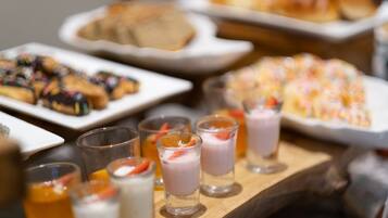 A buffet with various food items including pastries, desserts, and beverages.