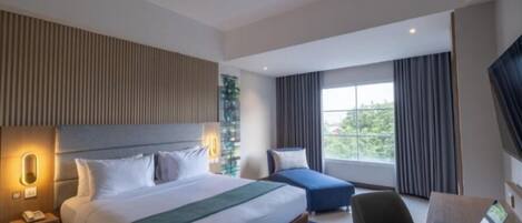 A modern hotel room with a large bed, a desk, and a laptop.